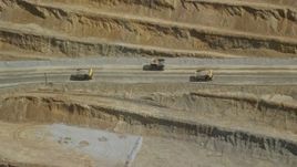 5.5K aerial stock footage of flying by gravel haulers in Kennecott Copper Mine, aka Bingham Canyon Mine, Utah Aerial Stock Footage | AX130_054