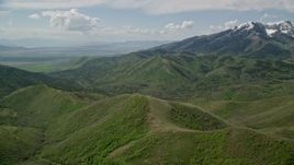 5.5K aerial stock footage of flying over green ridges, approaching snowy peaks, Oquirrh Mountains, Utah Aerial Stock Footage | AX130_062E