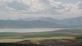 5.5K aerial stock footage of flying by circular crop fields, distant snow-capped peak and Utah Lake, Utah Aerial Stock Footage | AX130_082E