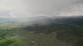 5.5K aerial stock footage of flying by rain falling on mountains, trees, near farming community, Fishlake National Forest, Utah Aerial Stock Footage | AX130_215