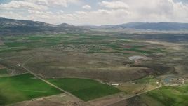 5.5K aerial stock footage of approaching small rural town, farmland, distant mountains, Loa, Utah Aerial Stock Footage | AX130_231E