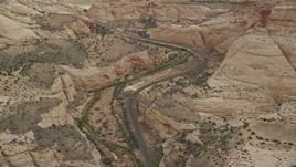 5.5K aerial stock footage of passing by desert road through Waterpocket Fold rock formations, mesas, Capitol Reef National Park, Utah Aerial Stock Footage | AX130_298E