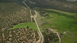 5.5K aerial stock footage of flying by Route 12, green fields, hills covered in vegetation, tilt to reveal small town, Boulder, Utah Aerial Stock Footage | AX130_364E
