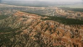 5.5K aerial stock footage of flying by long mesa with trees, desert vegetation, Bryce Canyon National Park, Utah Aerial Stock Footage | AX130_424E