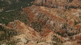 5.5K aerial stock footage of flying by buttes by canyon, trees, desert vegetation, Bryce Canyon National Park, Utah Aerial Stock Footage | AX130_448