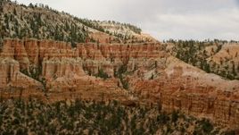 5.5K aerial stock footage of passing by group of hoodoos beside a mesa, Bryce Canyon National Park, Utah Aerial Stock Footage | AX130_472