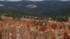 5.5K aerial stock footage of flying by Pink Cliffs, hoodoos, topped with trees, Bryce Canyon National Park, Utah Aerial Stock Footage | AX131_024