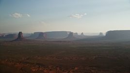 5.5K aerial stock footage of a view of buttes and mesas across desert valley, Monument Valley, Utah, Arizona, twilight Aerial Stock Footage | AX133_020