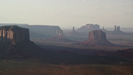 5.5K aerial stock footage of flying by buttes in a wide desert valley, Monument Valley, Utah, Arizona, twilight Aerial Stock Footage | AX133_065E