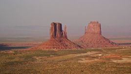 5.5K aerial stock footage of passing by West and East Mitten Buttes, Monument Valley, Utah, Arizona, twilight Aerial Stock Footage | AX133_082E