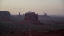 5.5K aerial stock footage of flying by buttes in a hazy desert valley, Monument Valley, Utah, Arizona, sunset Aerial Stock Footage | AX133_192E