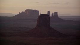 5.5K aerial stock footage of East Mitten Butte in a hazy valley, Monument Valley, Utah, Arizona, sunset Aerial Stock Footage | AX133_196