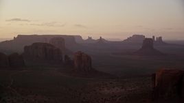 5.5K aerial stock footage of passing by buttes and mesas in hazy Monument Valley, Utah, Arizona, twilight Aerial Stock Footage | AX133_212