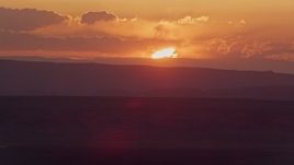 5.5K aerial stock footage of flying by sun setting behind mesas in Monument Valley, Utah, Arizona, sunset Aerial Stock Footage | AX134_005E