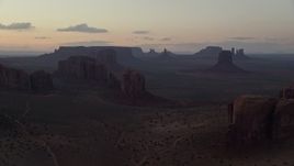 5.5K aerial stock footage of flying by desert buttes and mesas in hazy Monument Valley, Utah, Arizona, twilight Aerial Stock Footage | AX134_040E
