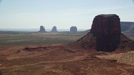 5.5K aerial stock footage of flying by buttes in hazy desert valley, Monument Valley, Utah, Arizona, sunset Aerial Stock Footage | AX135_007