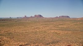 5.5K aerial stock footage of flying by distant buttes across a desert valley, Monument Valley, Utah, Arizona Aerial Stock Footage | AX135_083