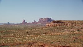 5.5K aerial stock footage of flying by distant buttes and desert valley, eclipsed by smaller butte, Monument Valley, Utah, Arizona Aerial Stock Footage | AX135_086