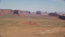 5.5K aerial stock footage of flying by distant buttes and mesas in a hazy desert valley, Monument Valley, Utah, Arizona Aerial Stock Footage | AX135_181
