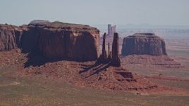 5.5K aerial stock footage of flying by a mesa and buttes in a hazy desert valley, Monument Valley, Utah, Arizona Aerial Stock Footage | AX135_184