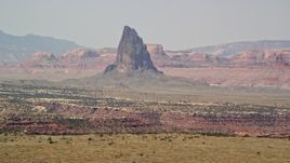 5.5K aerial stock footage of flying by tall butte in a hazy desert valley, Monument Valley, Utah, Arizona Aerial Stock Footage | AX135_185