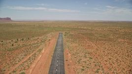5.5K aerial stock footage of flying over a runway toward wide desert valley, Monument Valley Airport, Utah Aerial Stock Footage | AX136_001