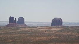 5.5K aerial stock footage of passing tall buttes and a hazy desert valley, Monument Valley, Utah, Arizona Aerial Stock Footage | AX136_004E