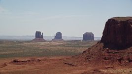 5.5K aerial stock footage of four desert buttes in a hazy valley, Monument Valley, Utah, Arizona Aerial Stock Footage | AX136_006E