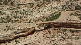 5.5K aerial stock footage of flying away from Owachomo Bridge, Natural Bridges National Monument, Utah Aerial Stock Footage | AX136_122E