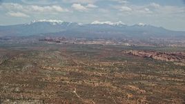 5.5K aerial stock footage of a wide view of rock formations, snow-capped mountains, Arches National Park, Utah Aerial Stock Footage | AX137_006E