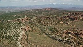 5.5K aerial stock footage fly over cliffs and desert plants toward Devil's Garden, Arches National Park, Utah Aerial Stock Footage | AX137_042E