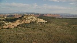5.5K aerial stock footage of approaching a rock overlooking a canyon, mesas in the background in Moab, Utah Aerial Stock Footage | AX138_244E