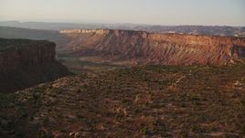 5.5K aerial stock footage of passing by a wide hazy desert canyon, Moab, Utah, sunset Aerial Stock Footage | AX138_361E