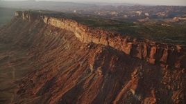 5.5K aerial stock footage of passing by canyon cliffs and hazy valley, Moab, Utah, sunset Aerial Stock Footage | AX138_364E