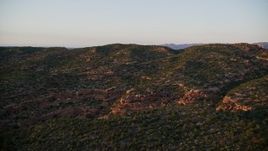 5.5K aerial stock footage of flying over hill, revealing Castle Valley and buttes in distance, Moab, Utah, sunset Aerial Stock Footage | AX138_391E