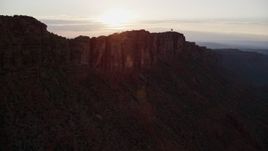 5.5K aerial stock footage of the sun setting behind mesa cliffs, Moab, Utah, sunset Aerial Stock Footage | AX138_393E