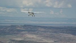 5.5K aerial stock footage of focusing on a Cessna airplane flying high above desert, partly cloudy, Emery County, Utah Aerial Stock Footage | AX139_129E