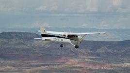 5.5K aerial stock footage of a view of a Cessna flying high above desert, ascend out of frame, Emery County, Utah Aerial Stock Footage | AX139_133E