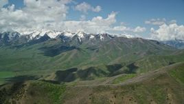 5.5K aerial stock footage view of snowy peak and green ridges, reveal Tecnam P2006T, Wasatch Range, Utah Aerial Stock Footage | AX140_136E