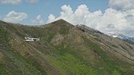 5.5K aerial stock footage of a Tecnam P2006T passing a green mountain, aspen trees, snow patches, Wasatch Range, Utah Aerial Stock Footage | AX140_139E
