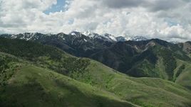 5.5K aerial stock footage of a wide view of lush green mountains, distant snowy peaks, Wasatch Range, Utah Aerial Stock Footage | AX140_233E