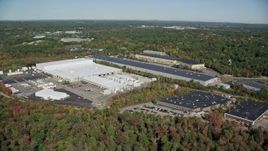 5.5K aerial stock footage flying by warehouses surrounded by trees in autumn, Westwood, Massachusetts Aerial Stock Footage | AX142_001E