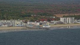 6K aerial stock footage flying by beach and pier, colorful autumn trees, Old Orchard Beach, Maine Aerial Stock Footage | AX147_295