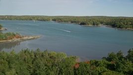 6K aerial stock footage flying over colorful forest, approach boat on Damariscotta River, autumn, Newcastle, Maine Aerial Stock Footage | AX148_014E