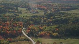5.5K aerial stock footage passing by a road winding through forest toward rural homes, fall foliage, Bar Harbor, Maine Aerial Stock Footage | AX148_229
