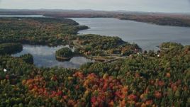 5.5K aerial stock footage flying over fall foliage toward a pond and coastal town, Bar Harbor, Maine Aerial Stock Footage | AX148_230