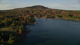 5.5K aerial stock footage flying away from coastal town among fall foliage and harbor, Blue Hill, Maine Aerial Stock Footage | AX149_022