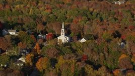 5.5K aerial stock footage flying away from a small town and white church among fall foliage, Blue Hill, Maine Aerial Stock Footage | AX149_029