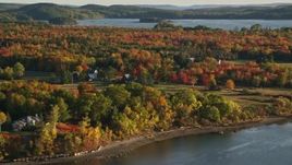5.5K aerial stock footage flying by rural waterfront homes, colorful forest, autumn, Penobscot, Maine Aerial Stock Footage | AX149_068