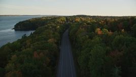 5.5K aerial stock footage flying over quiet road among a colorful forest in autumn, Stockton Springs, Maine, sunset Aerial Stock Footage | AX149_120E